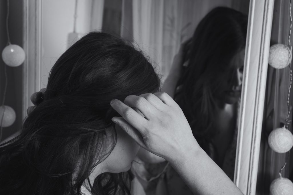 Woman adjusting her hair in front of a mirror
